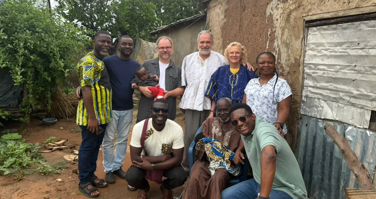 Visitors gathered with an elderly man seated outside his home during a community visit